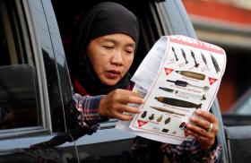 Photo of a woman reading a document at a military checkpoint in the Philippines before being permitted to return home after fighting between government troops and Islamic State militants.