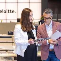 man and woman standing reviewing nots on tablet