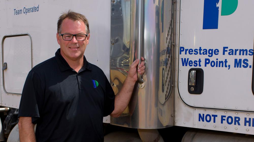 A man stands next to an 18-wheeler truck.