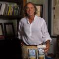 A man stands behind a table with 2 small bags labeled “Two Brooks Farm.” 