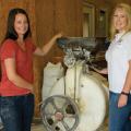 Two women stand on either side of a machine.