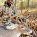 A man kneels beside a harvested buck.