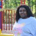 A woman stands outside in front of a playset.