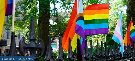 A close up of pride flags on the cast iron fence at Stonewall National Monument