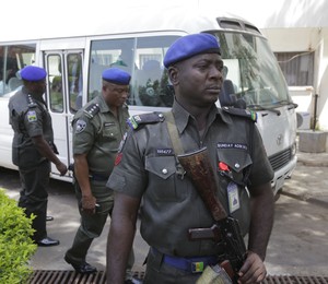 Homens da força de segurança da Nigéria protegem ônibus após atentado terrorista em Abuja, a capital do país (Foto: Sunday Alamba/AP)