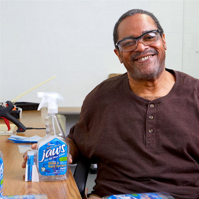 Smiling male employee applying labels to Jaws cleaning solution products