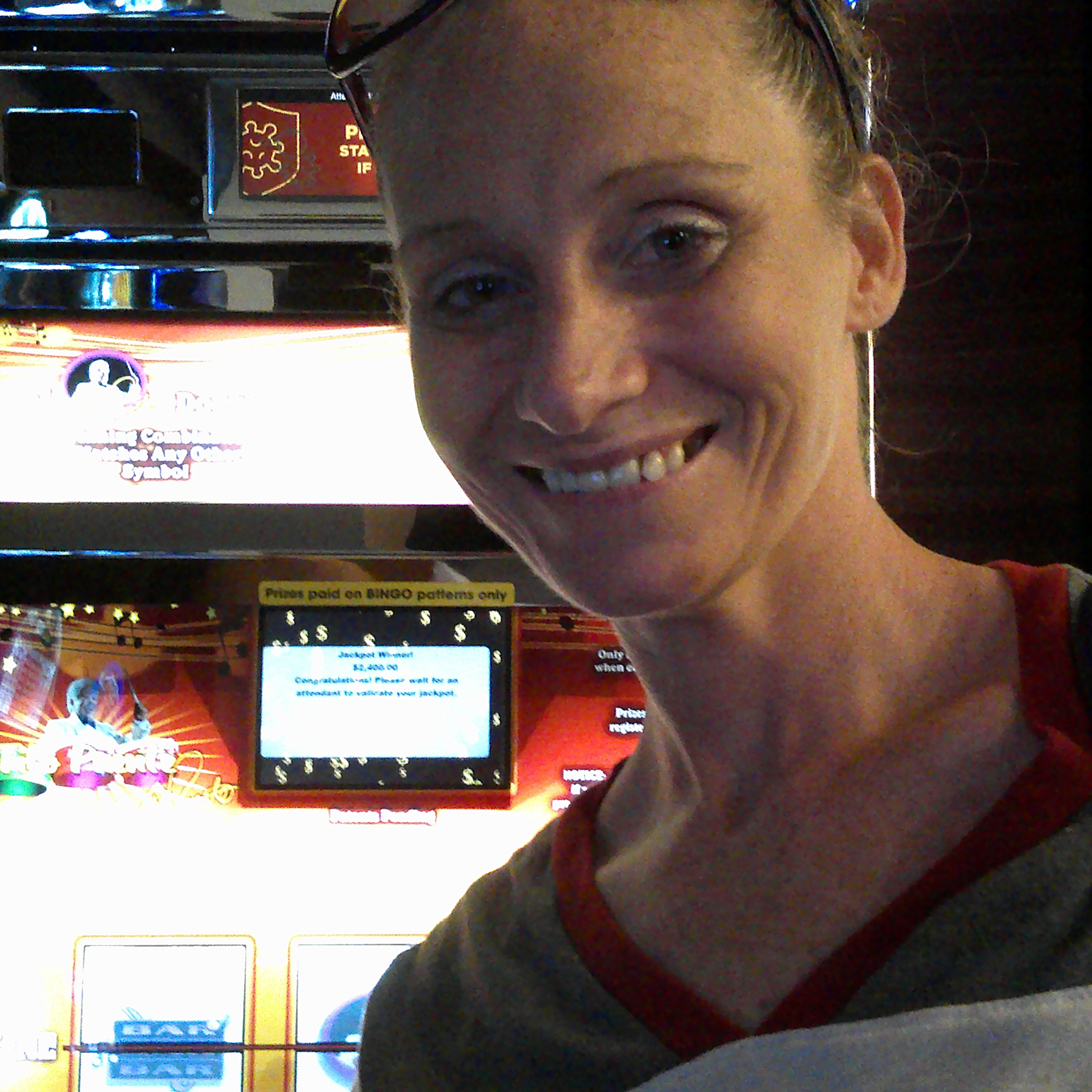 A woman smiling besides slot machine at 7th Street Casino