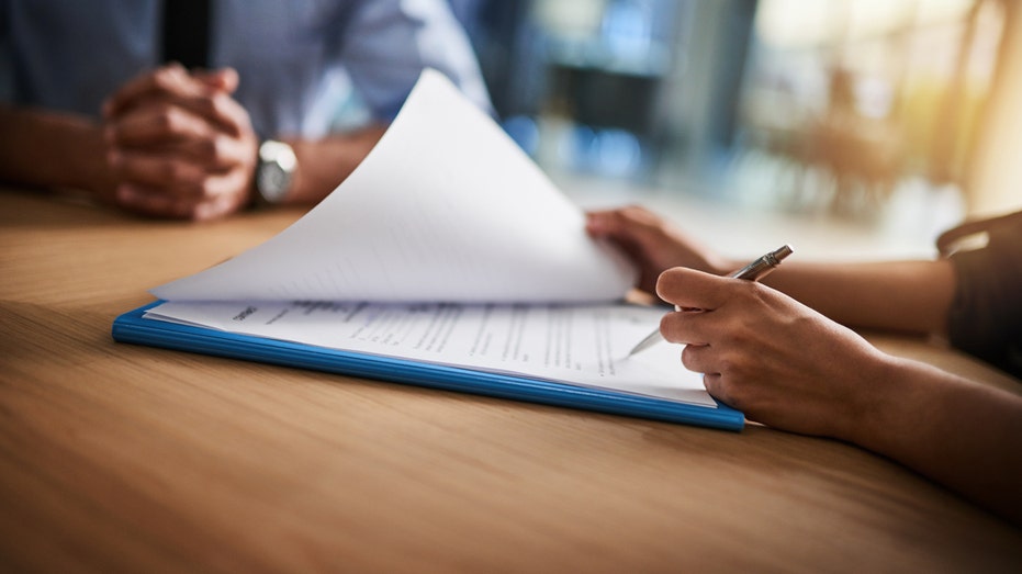 Recruiter looks at resume on clip board