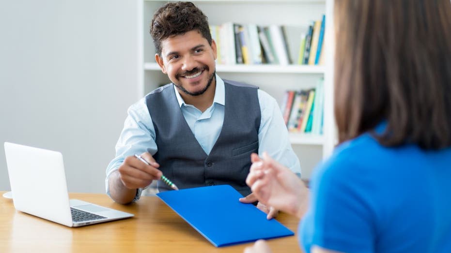 Man speaks to woman at interview desk