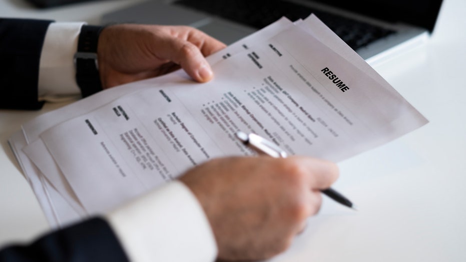 A pair of hands holds resume and pen