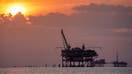 Offshore gas rigs are silhouetted against the setting sun on May 10, 2024, near Fort Morgan, AL. 