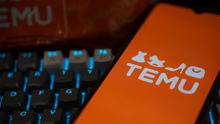 A mobile phone over a keyboard is seen with the logo of Temu on its screen.