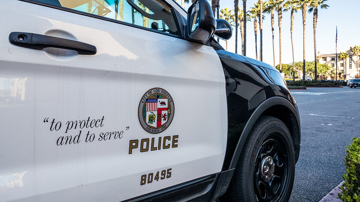 Los Angeles, USA - Close-up on the insignia and slogan of a LAPD vehicle, with the reflection of Union Station's tower visible in the car's window.