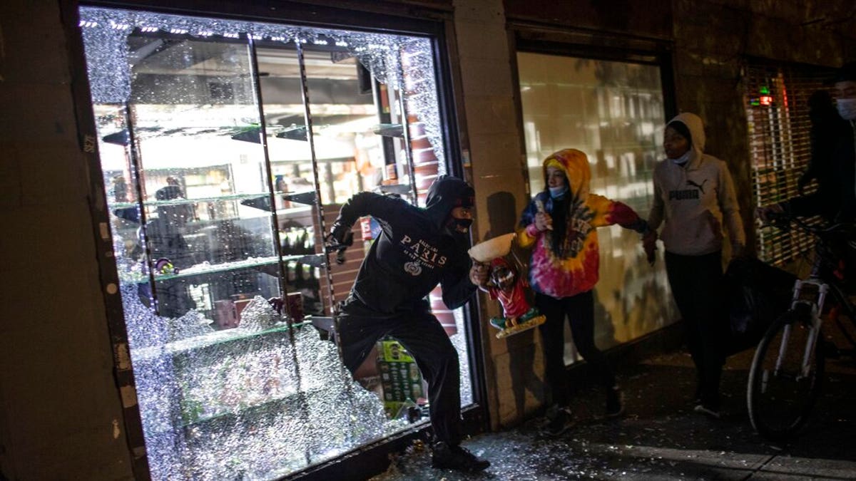 People run out of a broken-into smoke shop in New York City early Monday as police arrive. (AP)