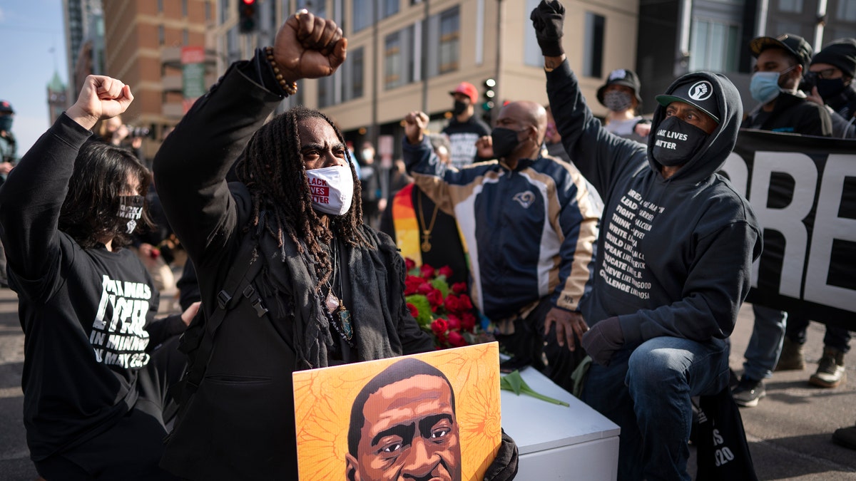 Cortez Rice, left, of Minneapolis, sits with others in the middle of Hennepin Avenue on Sunday, March 7, 2021, in Minneapolis, Minn., to mourn the death of George Floyd a day before jury selection is set to begin in the trial of former Minneapolis officer Derek Chauvin, who is charged in Floyd's death. (Jerry Holt/Star Tribune via AP, File)