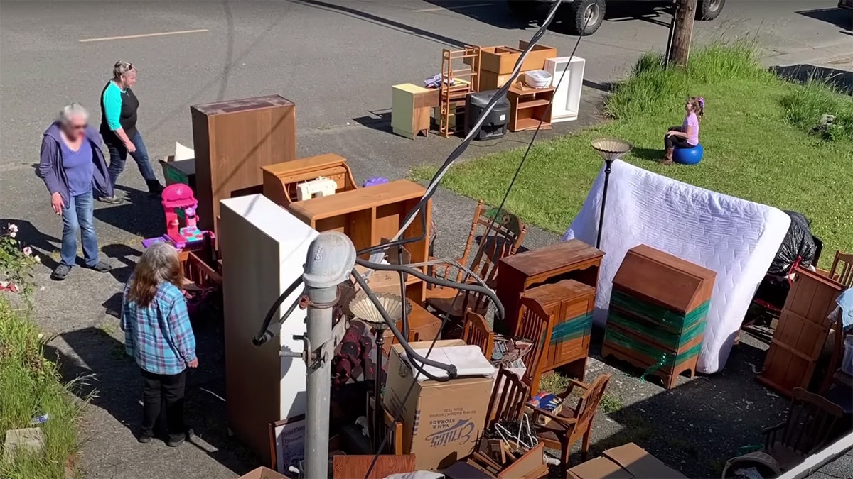 Accused squatters stand in a Northern California driveway near furniture and other belongings