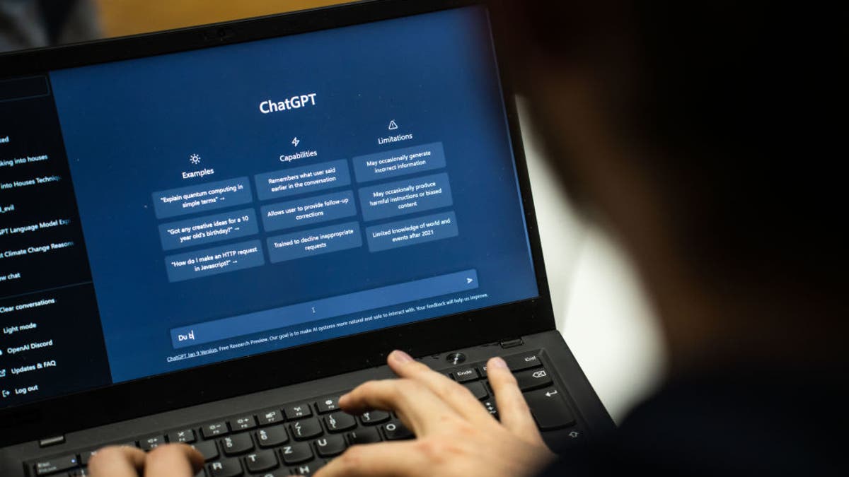 A person uses OpenAI's ChatGPT software on a computer laptop, typing on the keyboard.