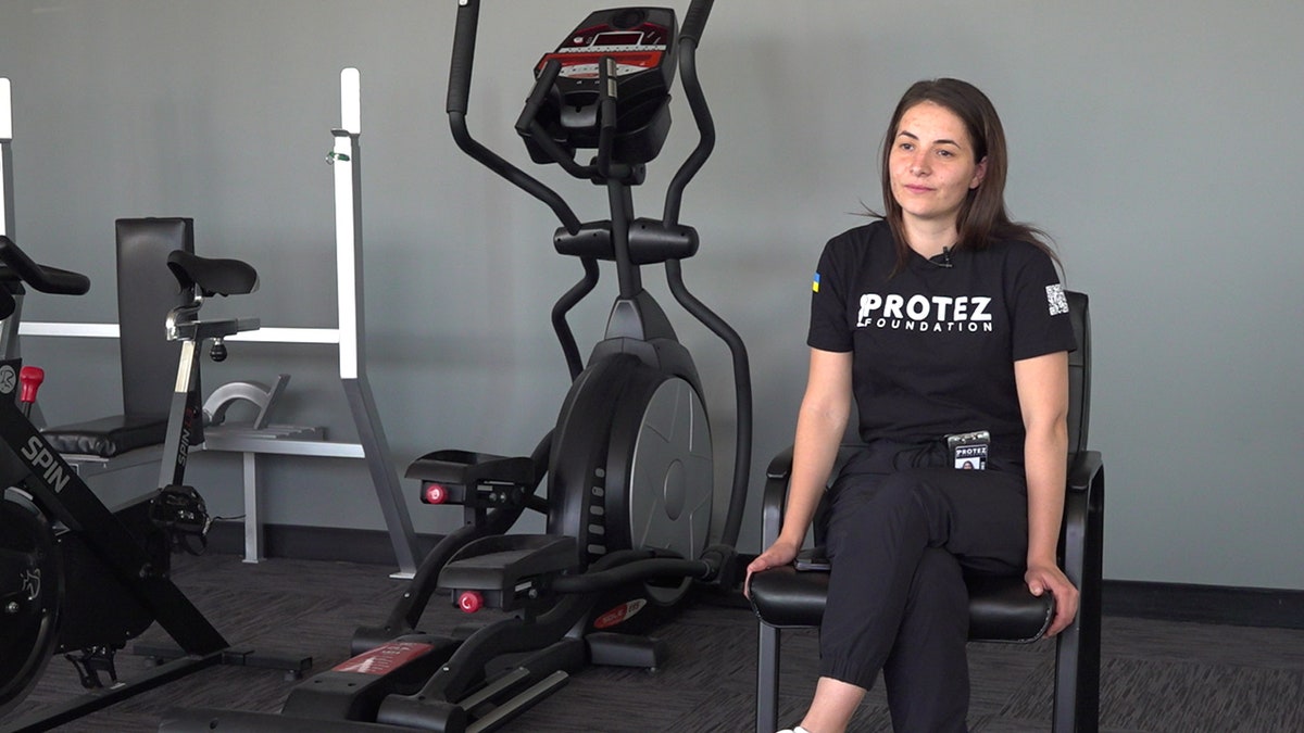 photo of a ukrainian woman sitting on a workout bench in a rehab center in the US