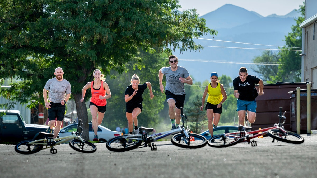 Racers run up a street toward bicycles laying on the ground for the title of "King and Queen" of The Alpine Training Center Gym in Boulder, Colorado