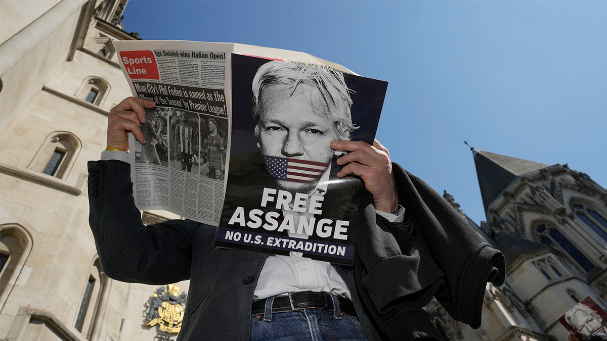 A protester reads a newspaper outside the High Court in London