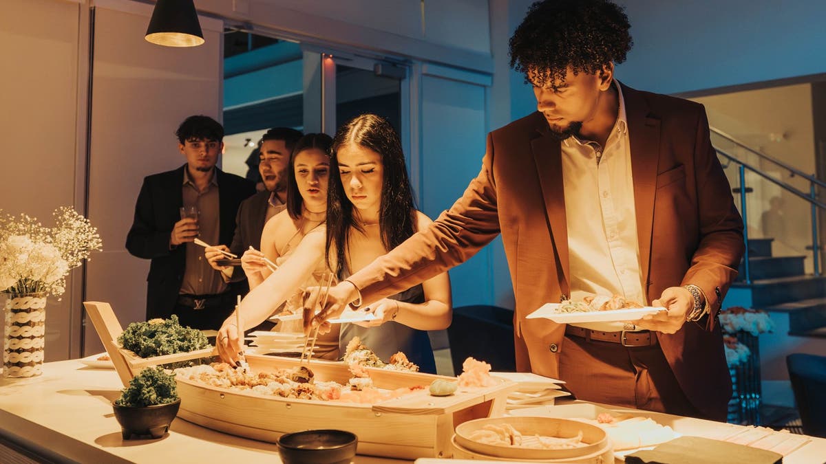 Guests select sushi during a dinner party catered by Irimaki Live Sushi Catering.