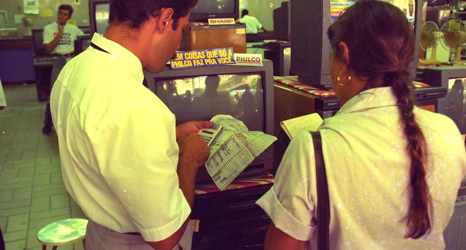 Conversão. Vendedor usa tabela para converter preço dos eletrodomésticos à URV