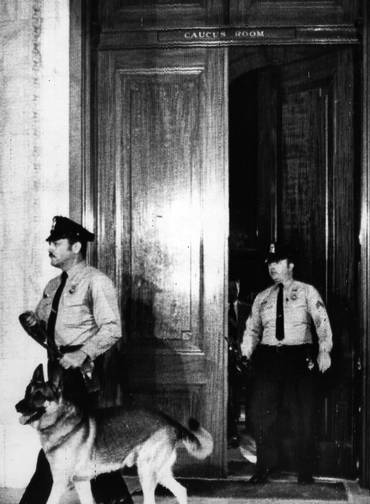 Julgamento. Policiais com cães treinados em busca de explosivos, após um alarme falso de bomba, deixam a sala de sessões de watergate