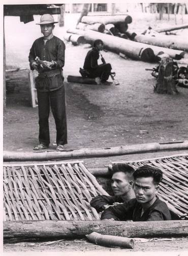 Guerra do Vietnã: guerrilheiros do vietcong, capturados por moradores do Vietnã do Sul, treinados pelos Estados Unidos, são mantidos presos em uma trincheira semicoberta por grades feitas de bambu. O local da foto é um campo de treinamento no planalto central do Vietnã