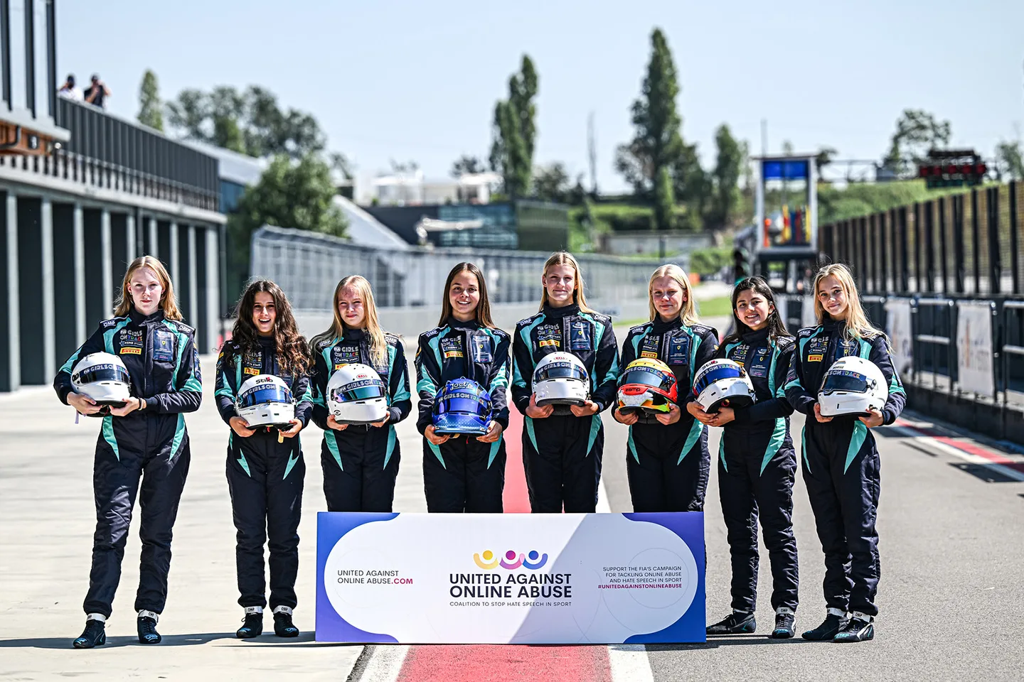 Group of young female drivers holding their race helmets in front of them