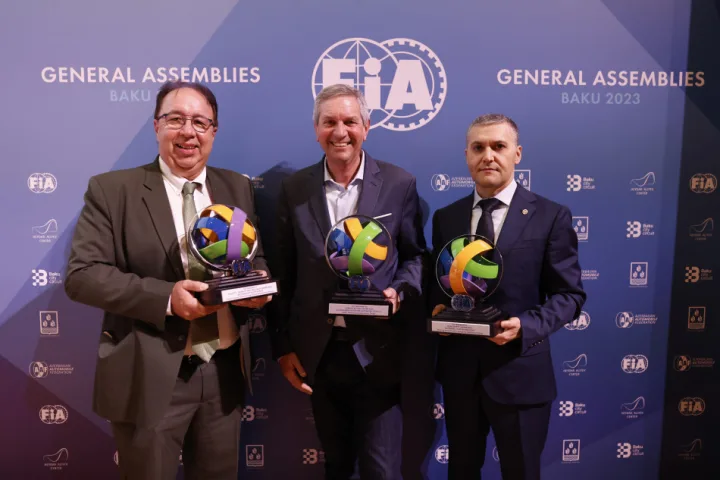 Three men holding trophies