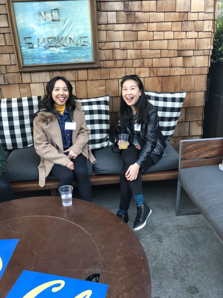 Two people sitting on a bench smiling at the camera