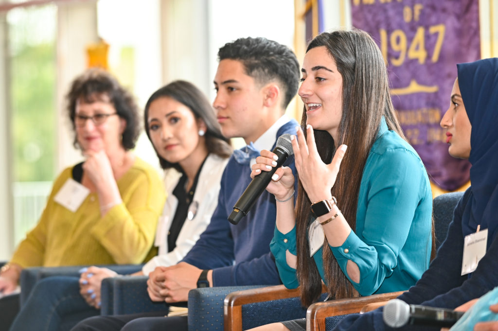 Panel of 5 people, person speaking into microphone