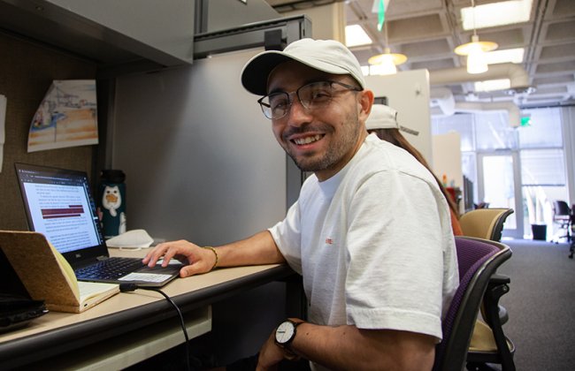 PhD student working at desk and smiling. 