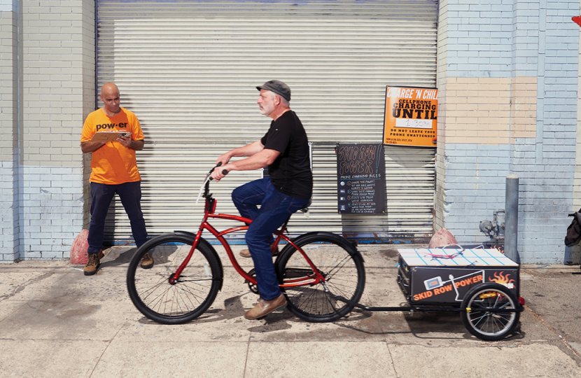 Photo of François Bar, professor of communication, pulling a solar-paneled cart designed to provide power to Skid Row residents’ mobile phones