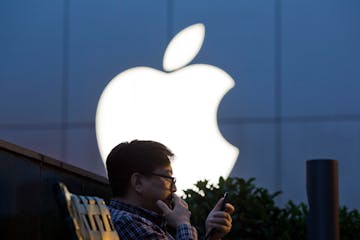 FILE - In this Friday, May 13, 2016, file photo, a man uses his mobile phone near an Apple store in Beijing. On Wednesday, July 12, 2017, Apple announ