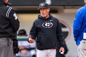 Georgia head coach Wes Johnson meets with umpire crew and UNC Asheville head coach Scott Friedholm during an NCAA baseball game in February.