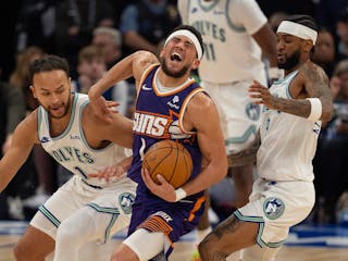 Suns guard Devin Booker gets pinched by Kyle Anderson and Nickeil Alexander-Walker, right, last Sunday.