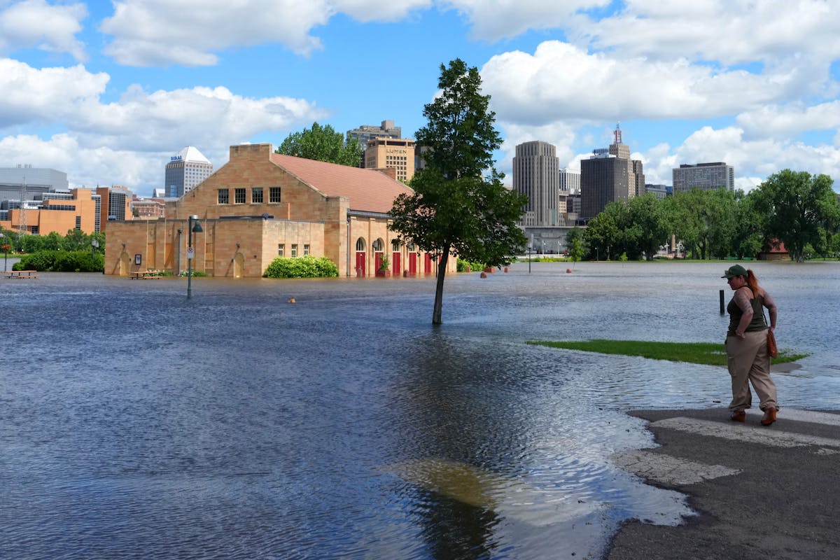 Onlookers take in the scene as rising water from the Mississippi River floods the Clarence W. Wigington Pavilion at Harriet Regional Park in St. Paul 