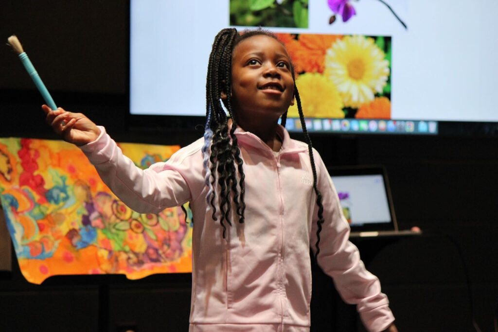 A student waves a paint brush