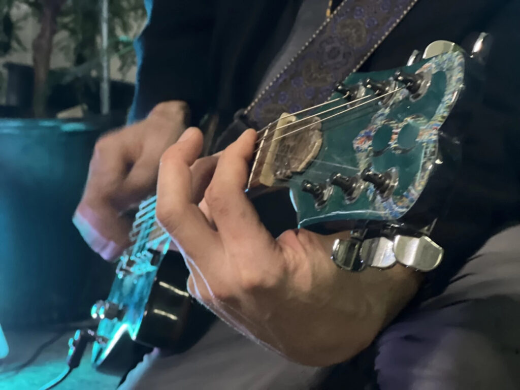 A close-up photo of hands playing an electric guitar.