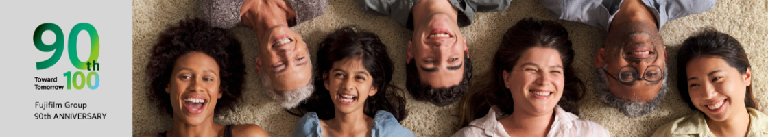 A diverse group of people gathering with smiles, lying down and looking up.