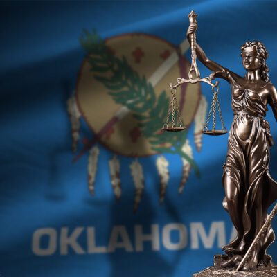 The justice statue in front of the Oklahoma state flag.