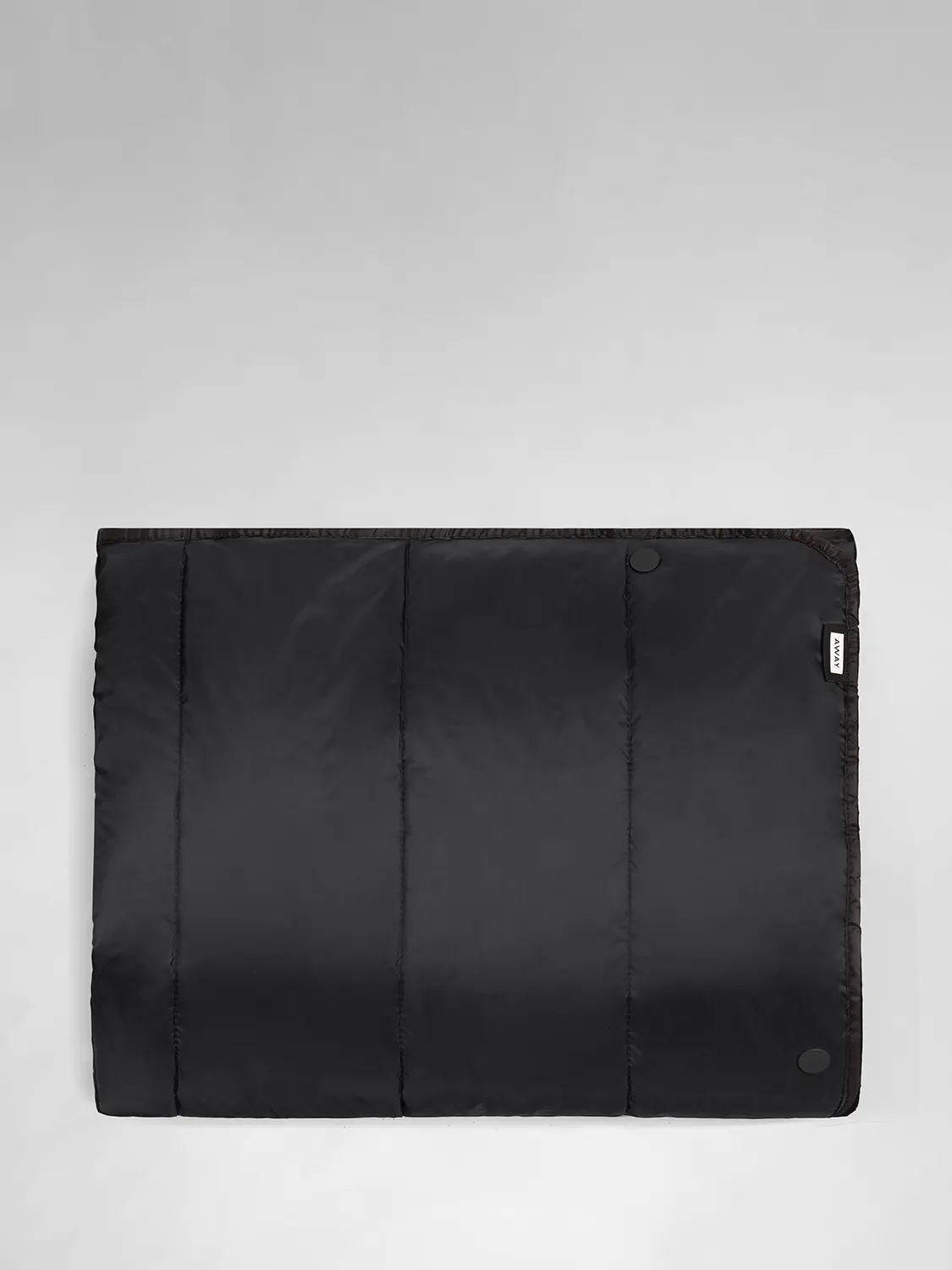 A black Away travel blanket laid flat front side up.