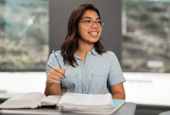 a student in a classroom with books on a desk