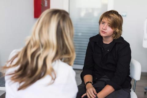 Teen in chair speaking with healthcare provider