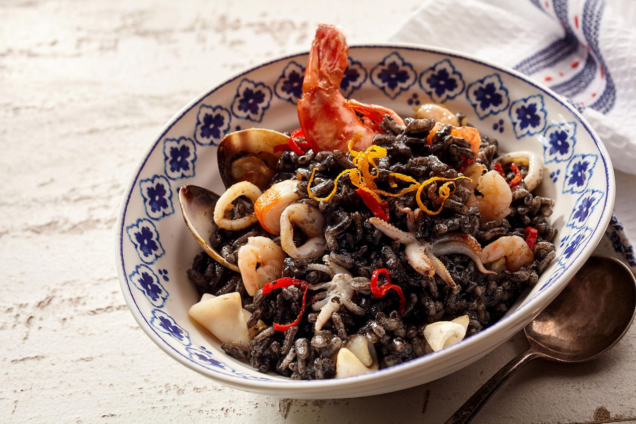 Nero, a seafood risotto, specialty dining dish with shrimp and scallops smothered in ink from squid, on a restaurant in Split, Croatia