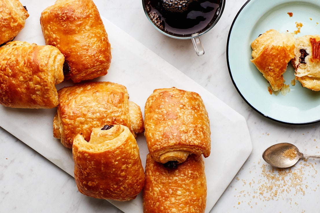 Chocolate croissants on a platter one removed to a plate and torn in half.