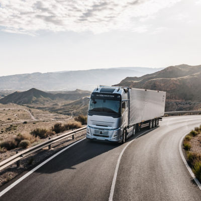 Volvo truck on the road, surrounded by mountains and cloudy sky