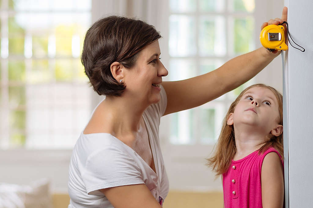 Mother taking height of her daughter