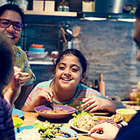 Family eats and laughs around kitchen table